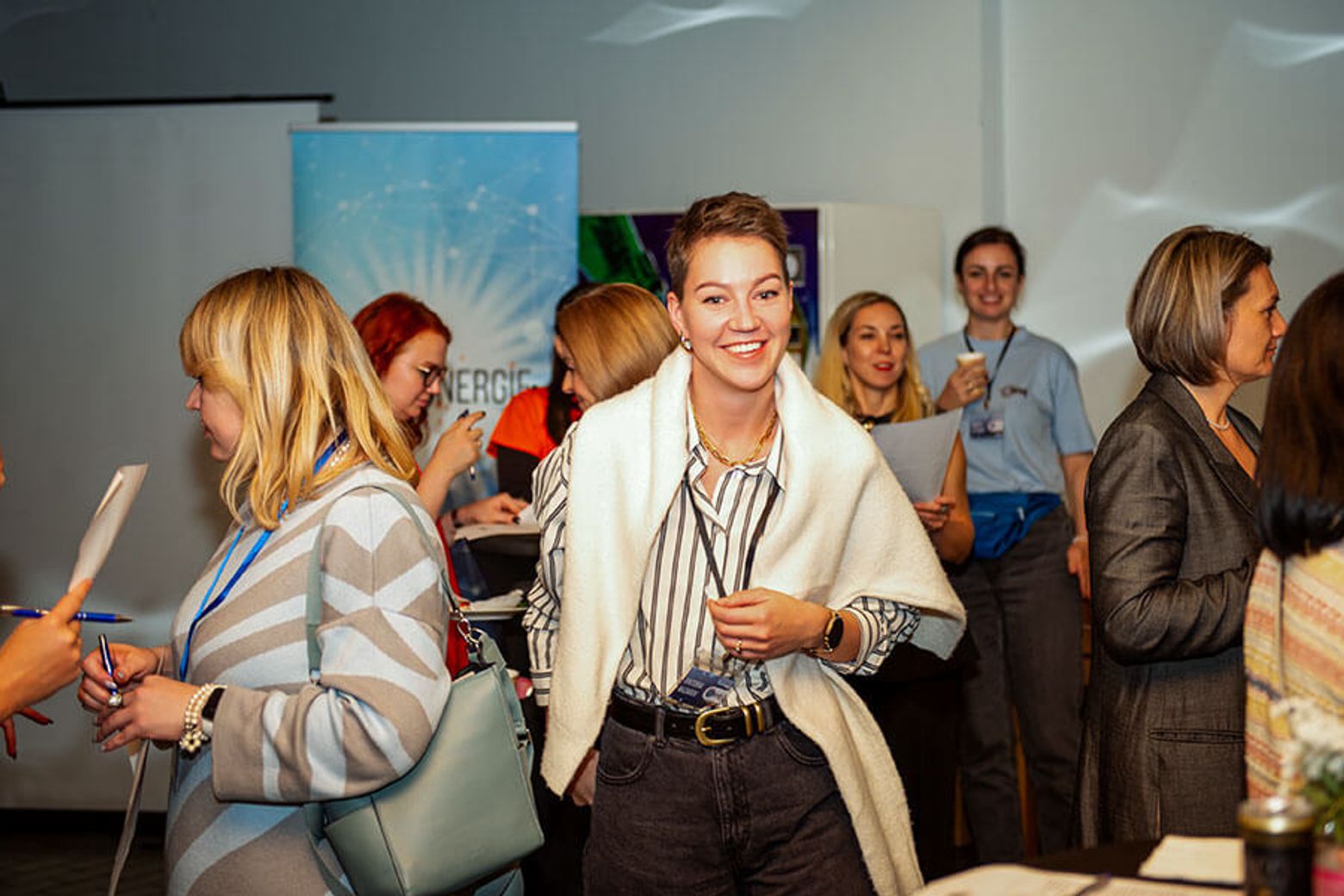 Viktoria Loginova holding a drink and talking with attendees at the Psynergie Forum.