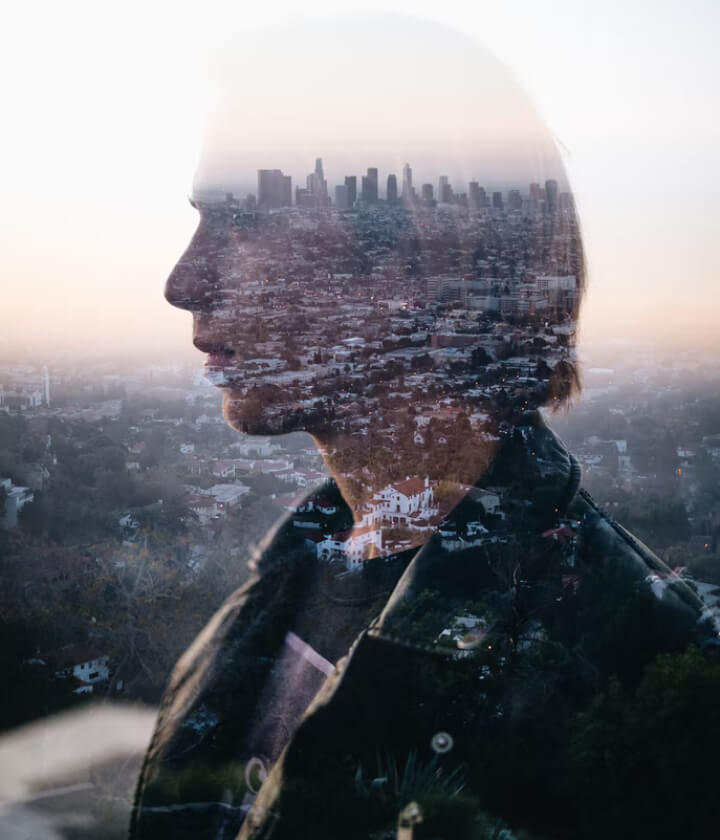 A person’s profile blended with a city landscape.
