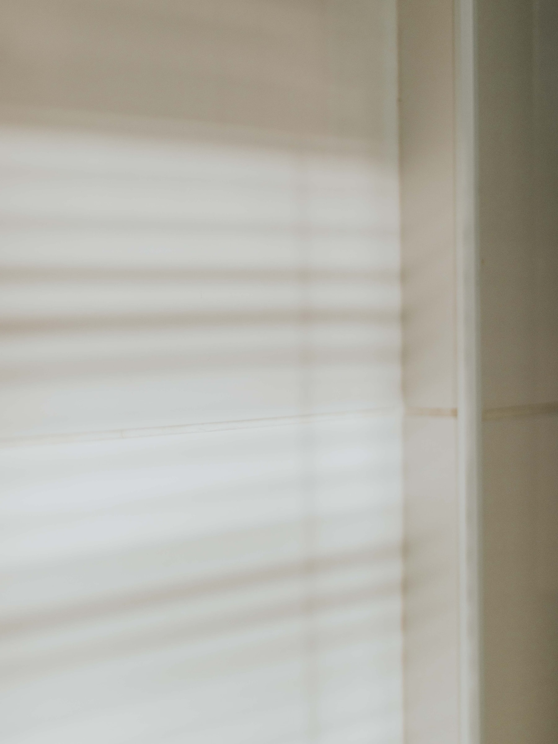 Soft horizontal bands of light and shadow across a pale wall.