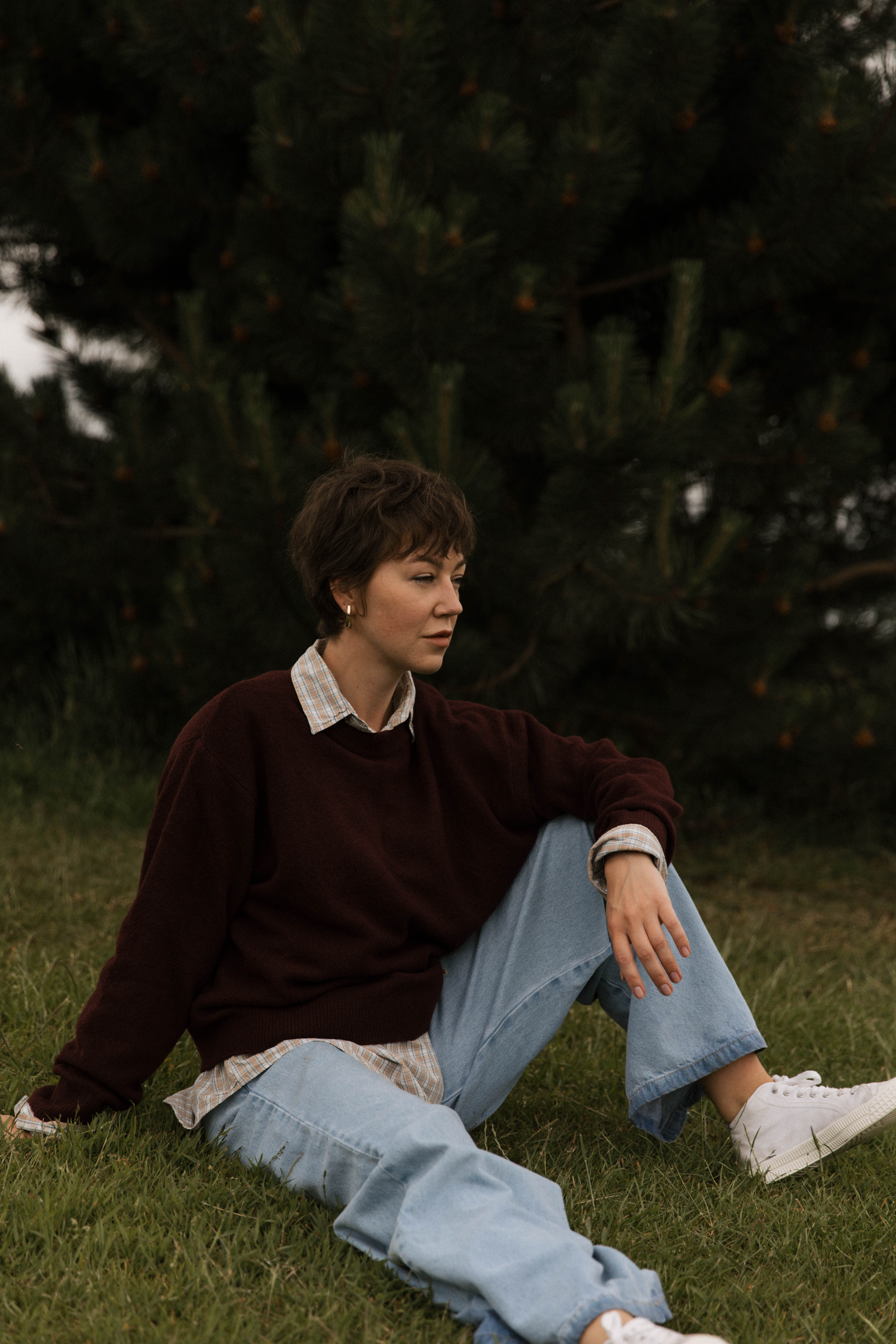 Viktoria Loginova sitting on the grass beside trees.