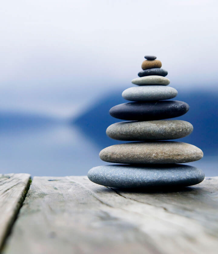 A stack of smooth stones beside water.