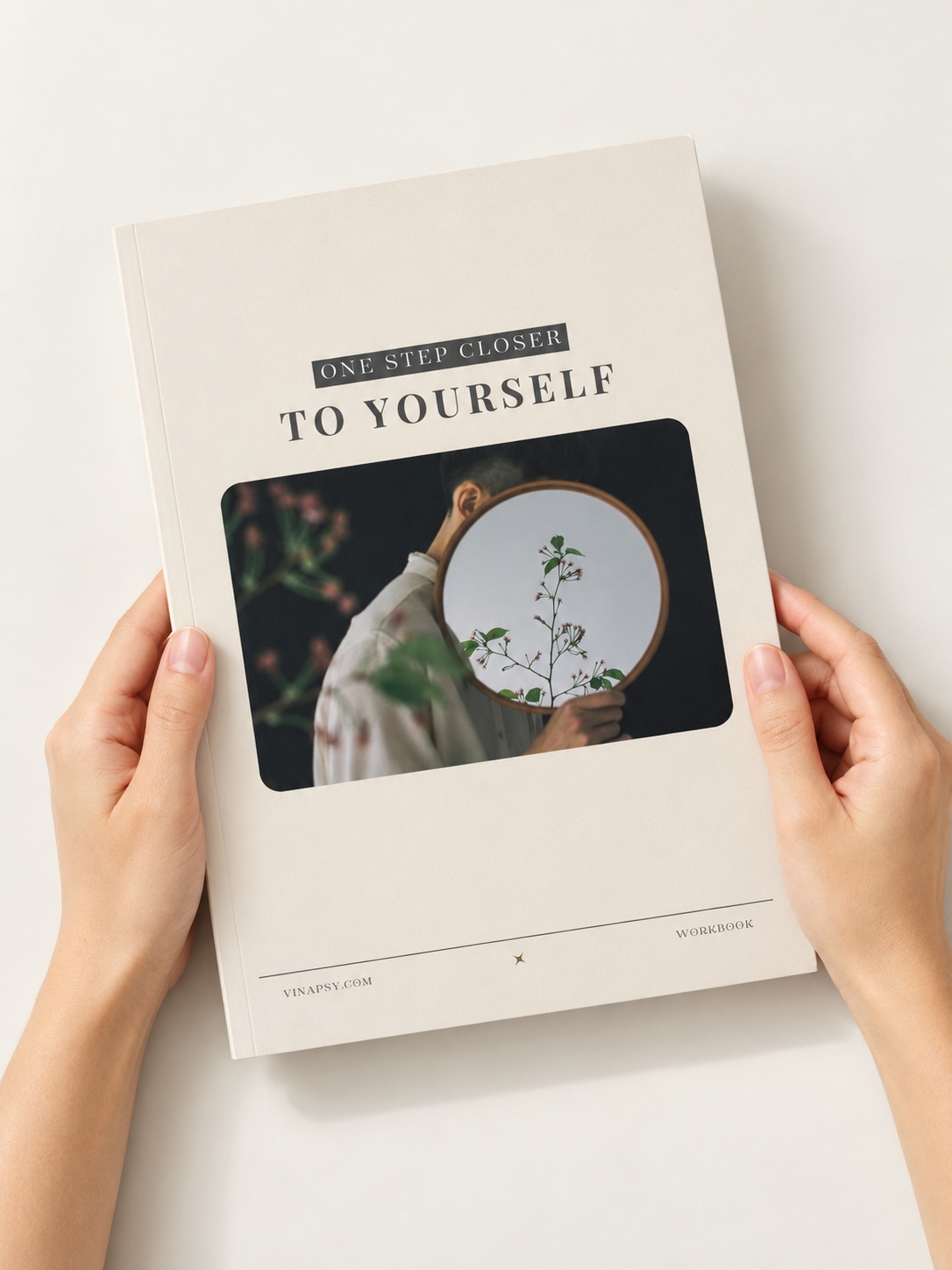 Hands holding the cover of One Step Closer to Yourself above a pale table.